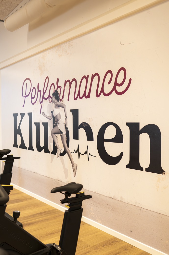 Indretning i Performance Klubben med motionscykler og vægdekoration i træningscenteret i Højbjerg.