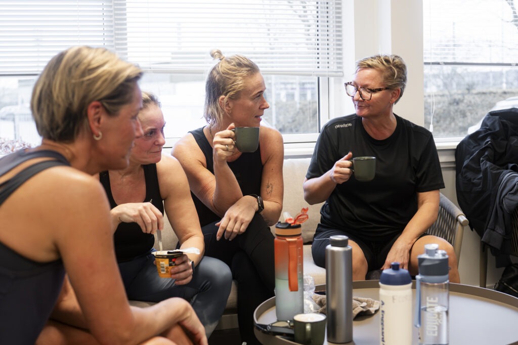 Kvinder i træningstøj drikker kaffe og hygger efter holdtræning i Performance Klubben, Højbjerg.