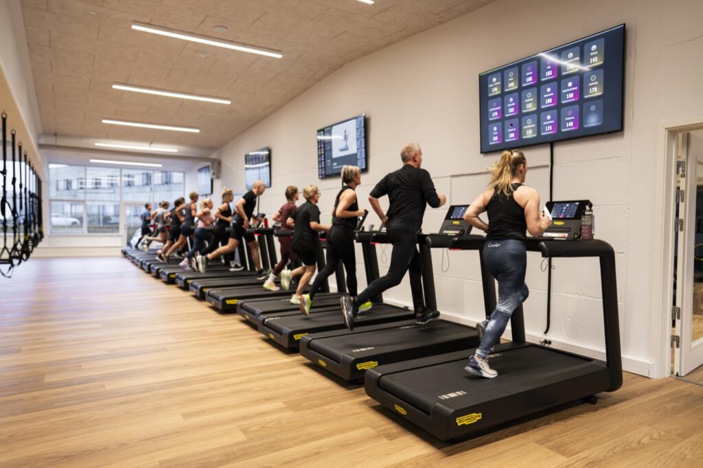 HIIT-hold løber intervaller på Technogym-løbebånd med live-puls på skærmen hos Performance Klubben i Højbjerg